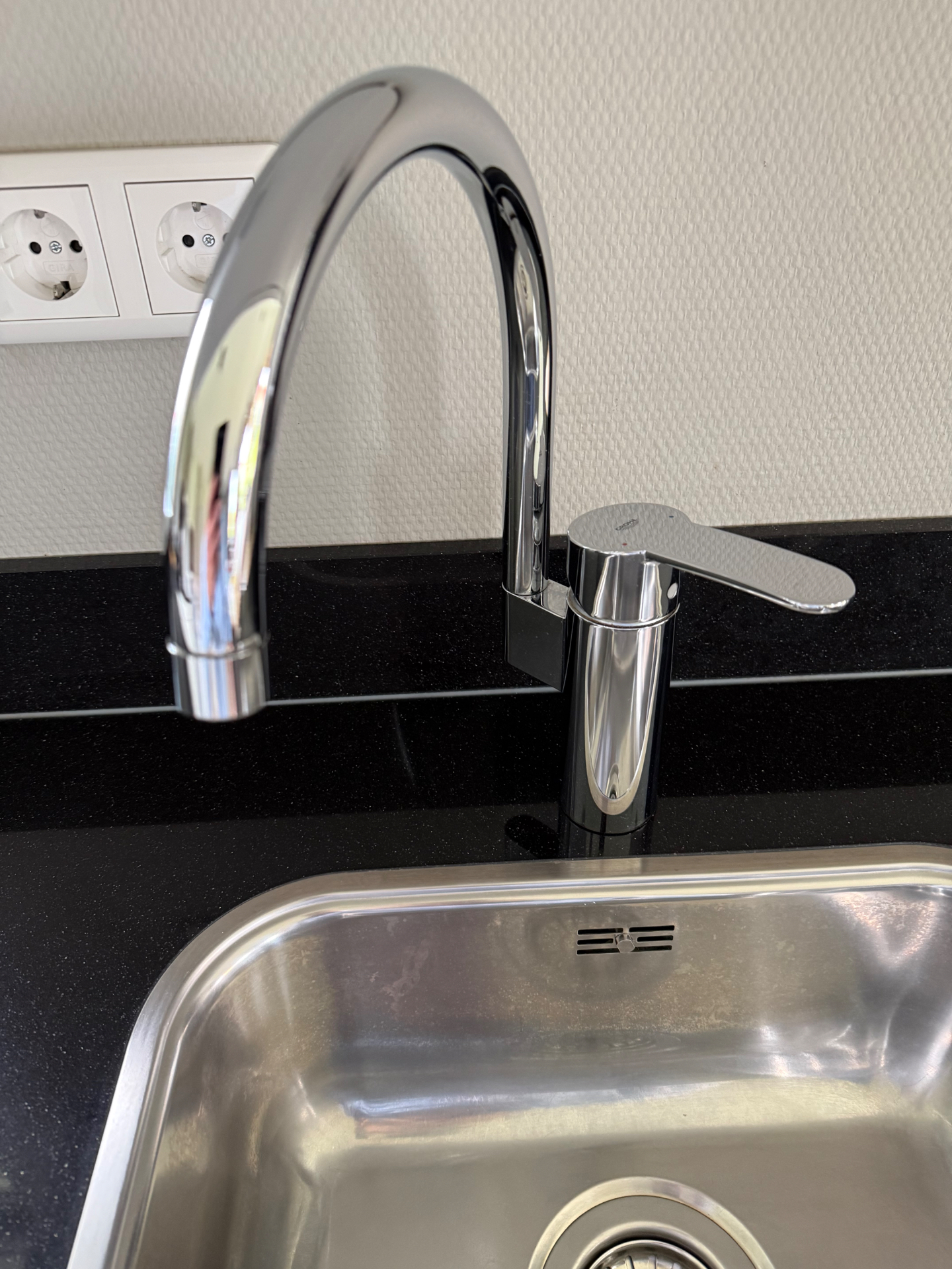Gepolijste chromen kraan boven roestvrijstalen spoelbak