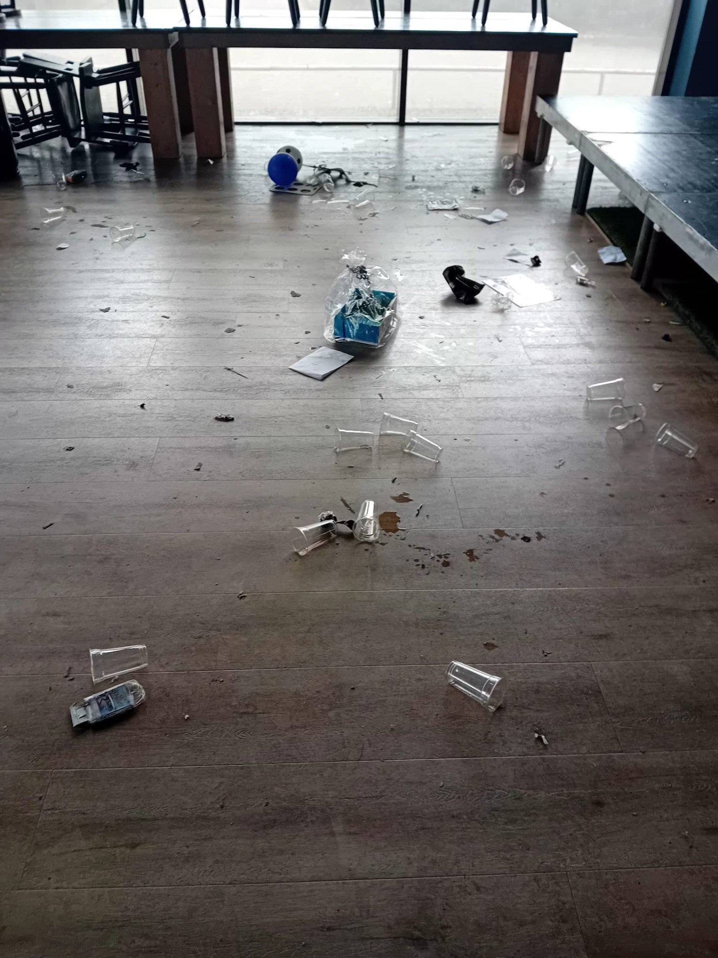 Vloer bezaaid met plastic bekers en restafval